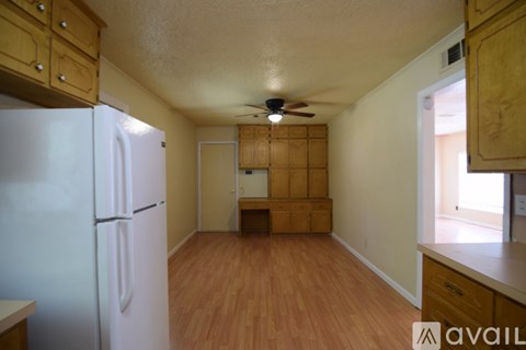 A kitchen with a white refrigerator and wooden floors.