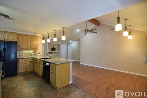 A kitchen with wooden cabinets and a black fridge.