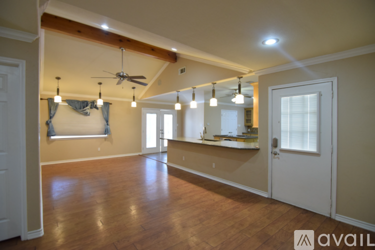 A spacious room with wooden floors and a ceiling fan.