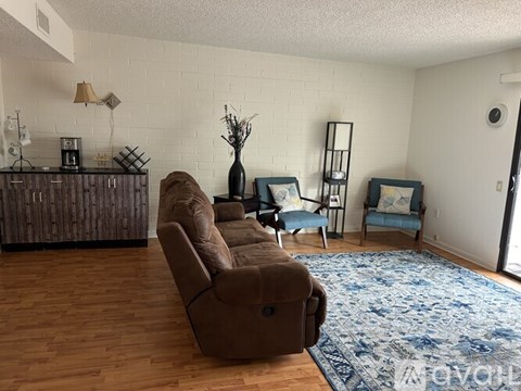 A living room with a brown couch and a blue rug.