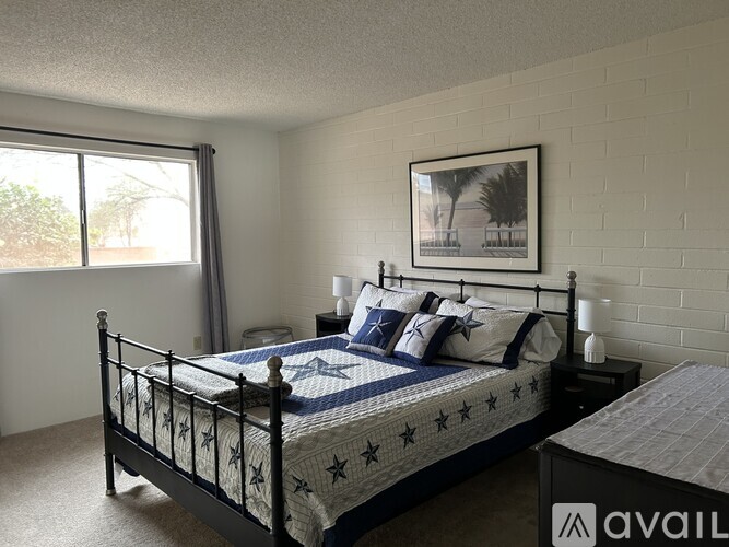 A bedroom with a bed, nightstand, and window.