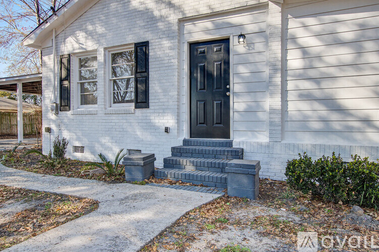 A white house with a black door and steps leading up to it.