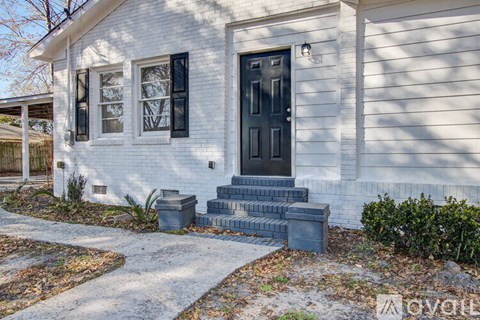 A white house with a black door and steps leading up to it.