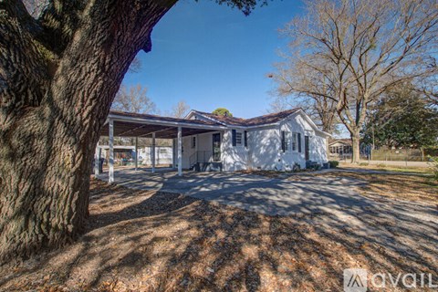 A house with a white exterior and a brown roof is surrounded by trees.
