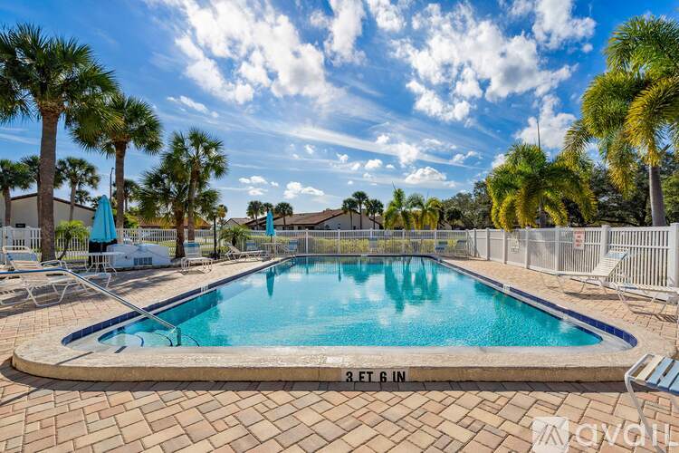 A pool surrounded by palm trees and a fence.
