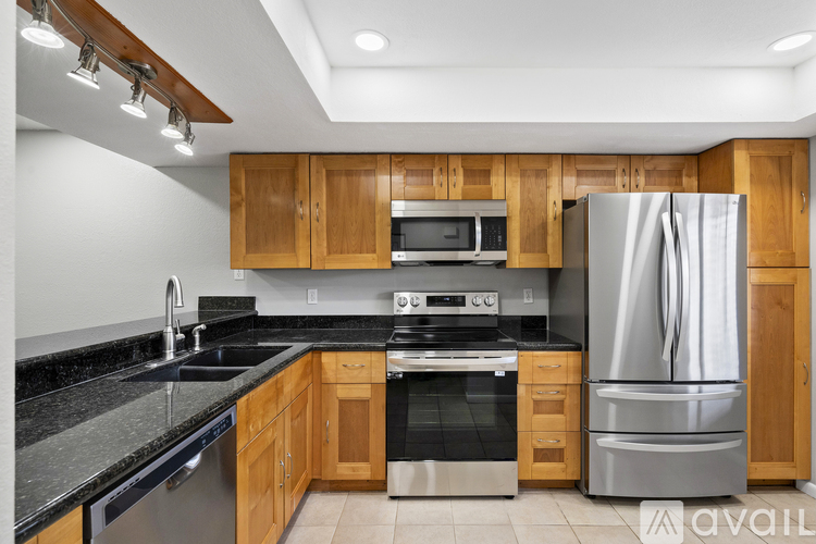 A kitchen with wooden cabinets and a stainless steel refrigerator.