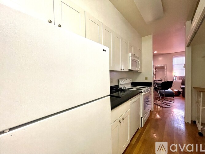A kitchen with white cabinets and a white refrigerator.