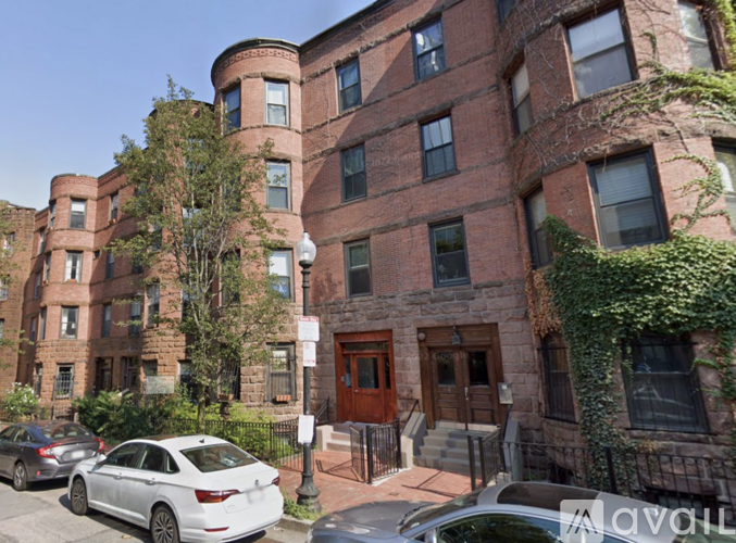 A white car is parked in front of a building with a brown door.