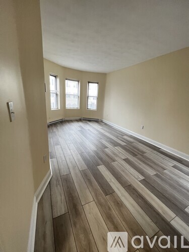 A room with wooden flooring and windows.