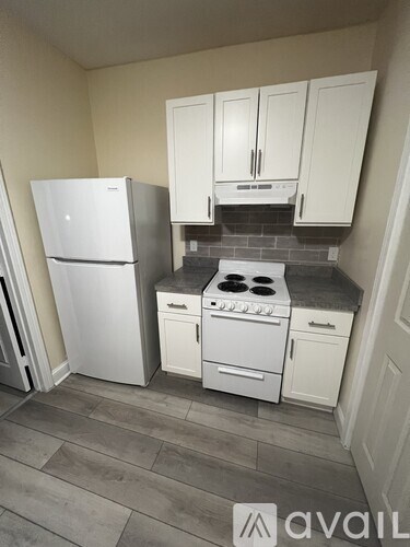A kitchen with a white fridge, stove and cabinets.