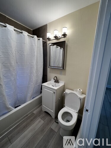 A small white toilet sits in a bathroom next to a shower curtain.