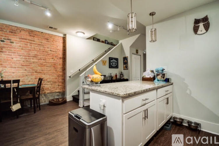 A kitchen with a brick wall and wooden floors.