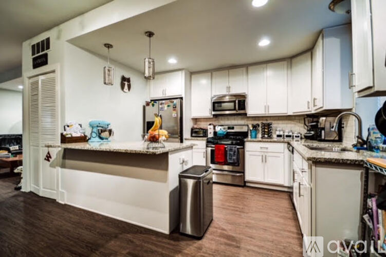 A kitchen with white cabinets and a wooden floor.