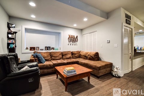 A living room with a brown couch and a black chair.