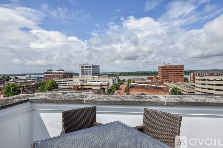 A balcony with two chairs and a table overlooks a cityscape.