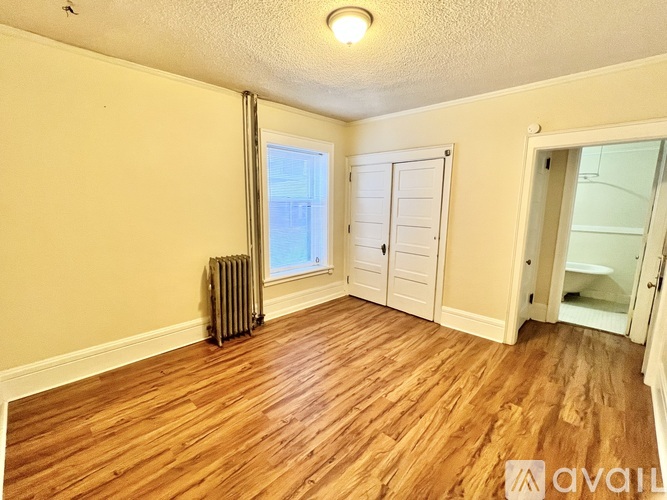 A room with wooden floors and a window with a closed white shutter.