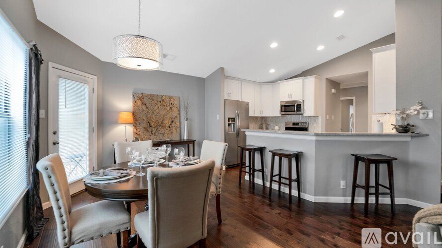 A modern dining room with a table set for two and a kitchen area in the background.