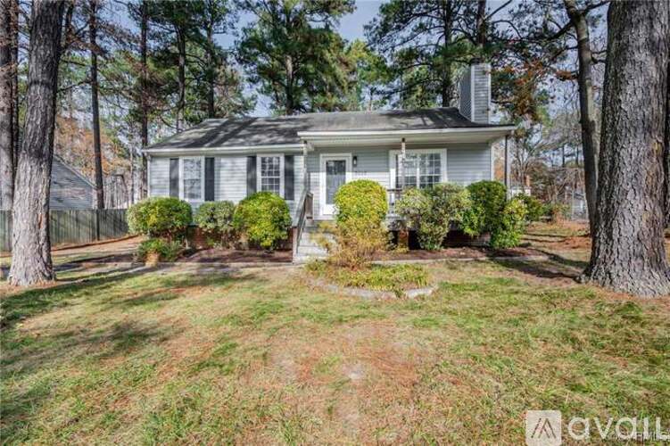 A house with a grey roof and white trim is surrounded by trees.