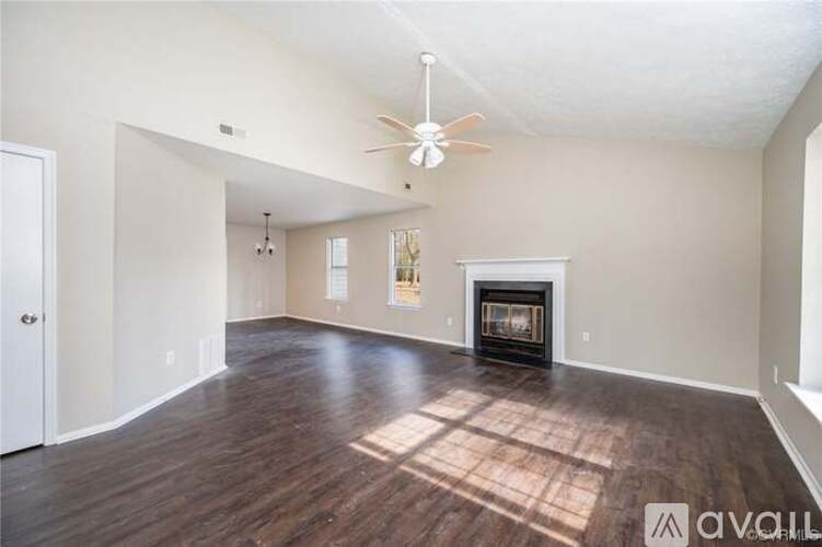 A spacious living room with a fireplace and a ceiling fan.