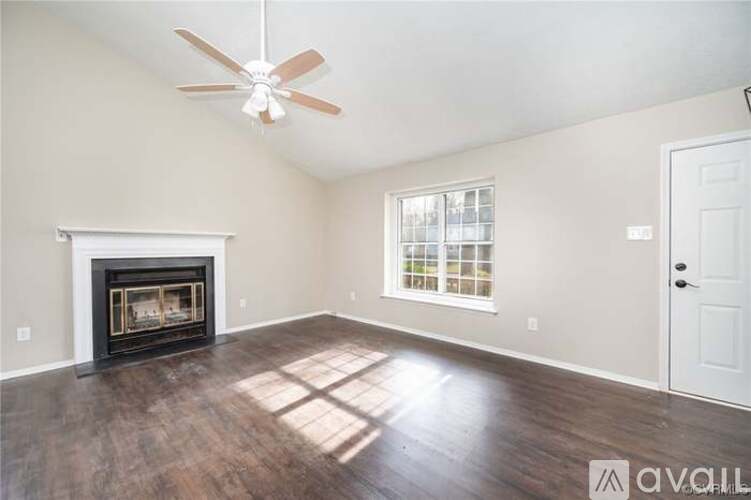 A living room with a fireplace and a ceiling fan.