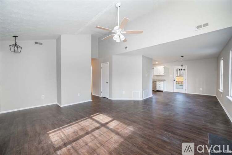 A spacious room with wood flooring and a ceiling fan.