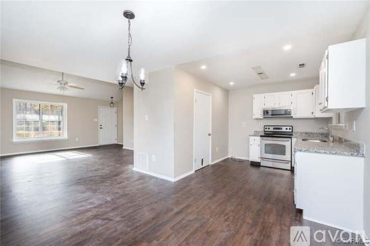 A kitchen with white cabinets and a wooden floor.