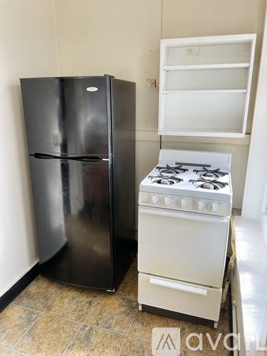 A black refrigerator and a white stove in a kitchen.