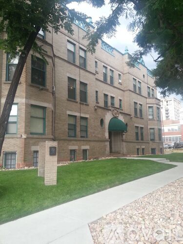 A building with a green roof and a walkway in front.