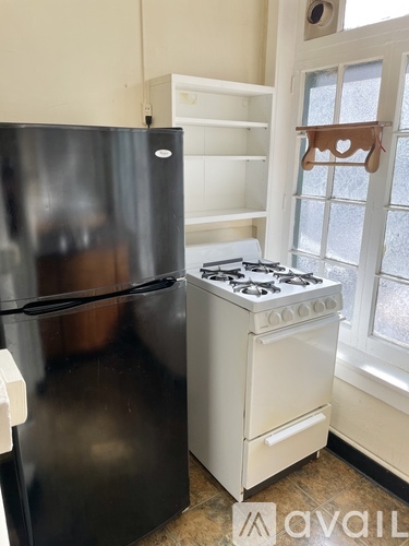 A black refrigerator is next to a white stove in a kitchen.