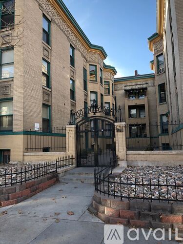A building entrance with a black iron fence and a stone wall.