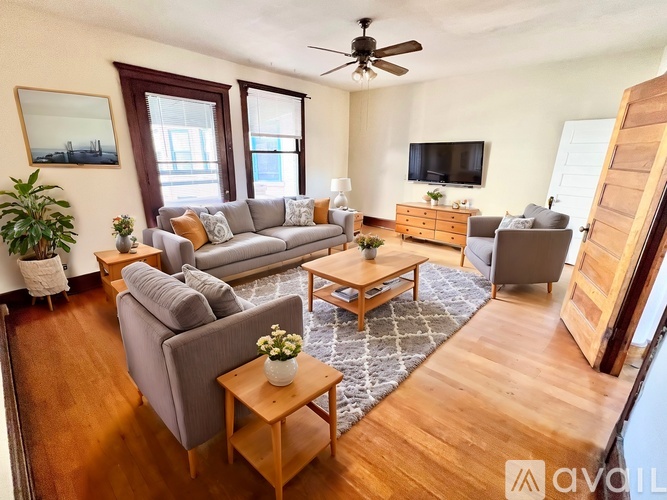 A living room with a grey couch, a wooden coffee table, and a flat screen TV mounted on the wall.