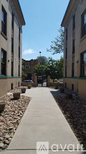 A long concrete walkway with rocks on either side leads to a building.