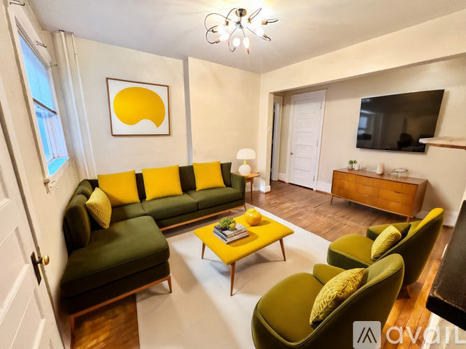 A living room with a yellow couch and green chairs.