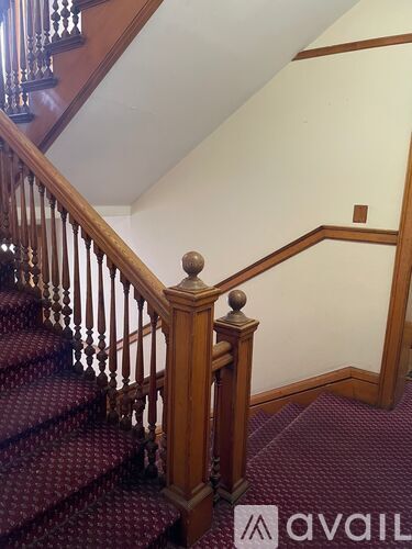 A staircase with a wooden banister and a red carpet.
