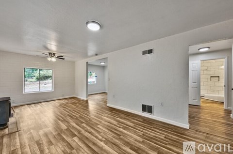 A spacious room with wooden flooring and a ceiling fan.