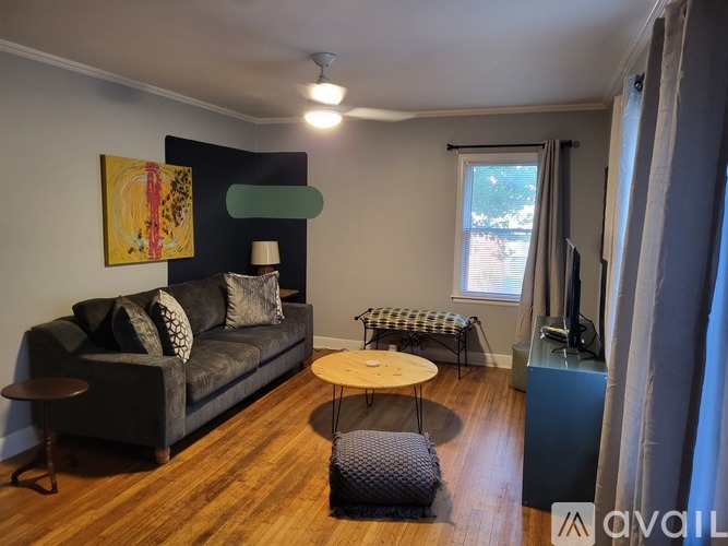 A living room with a grey couch, a wooden table, and a painting on the wall.