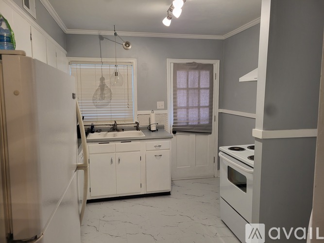 A kitchen with white cabinets and a marble floor.