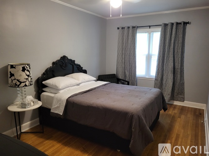 A bedroom with a bed, nightstand, and window.