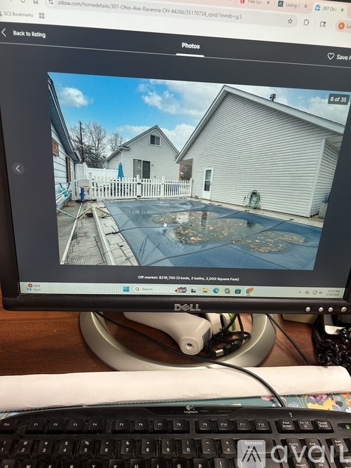 A computer monitor displays a photo of a house with a white picket fence.