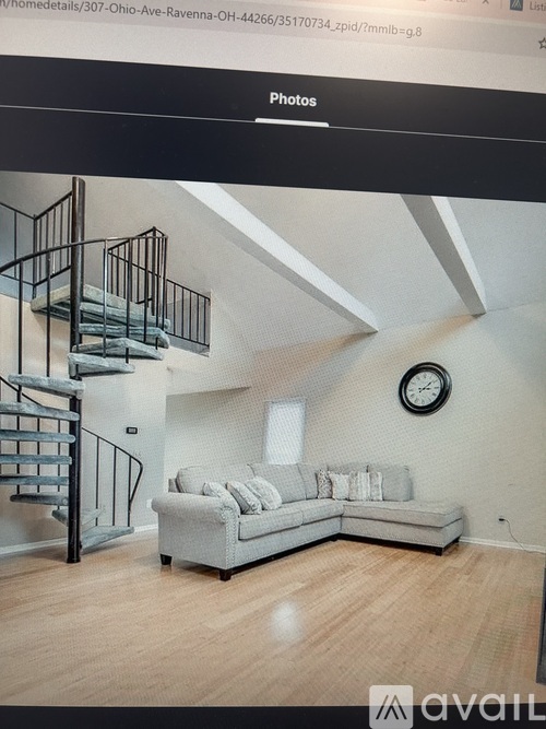 A living room with a grey couch and a black metal staircase.