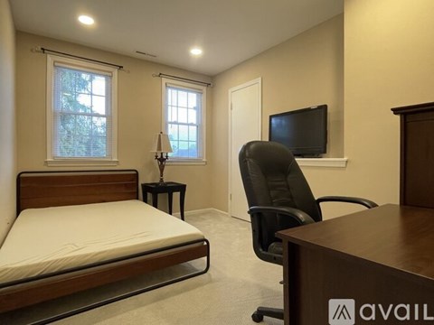 A bedroom with a bed, desk, and chair.