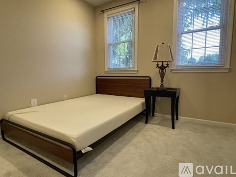A bedroom with a bed, table, and lamp.