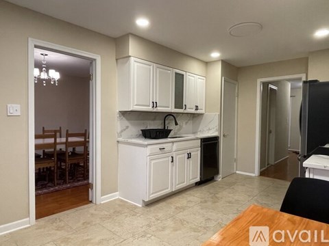 A kitchen with white cabinets and a black refrigerator.