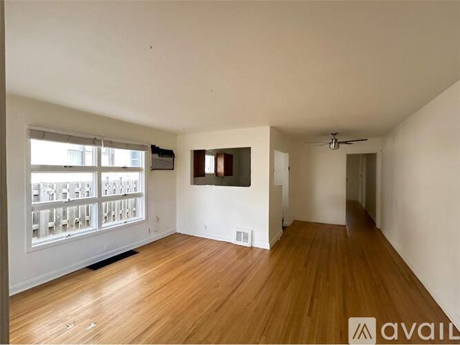 A spacious room with wooden floors and a large window.