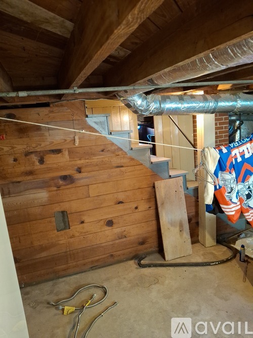 A room with wooden walls and a staircase in the background.