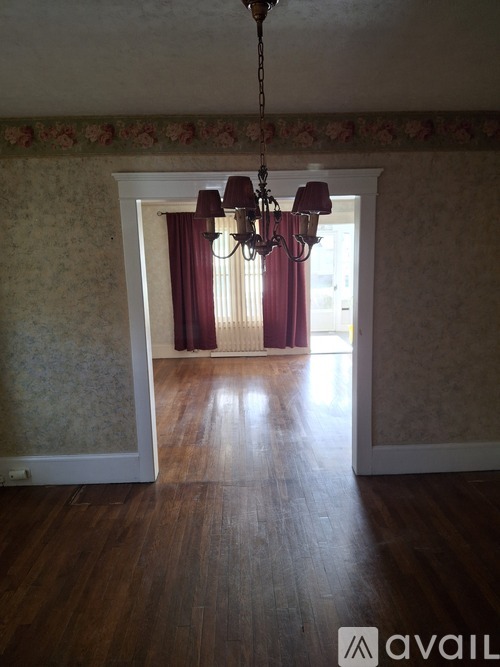 A room with a chandelier and a window with curtains.