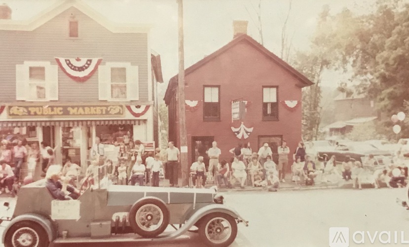 A vintage photo of a public market with a car in the foreground.