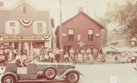 A vintage photo of a public market with a car in the foreground.