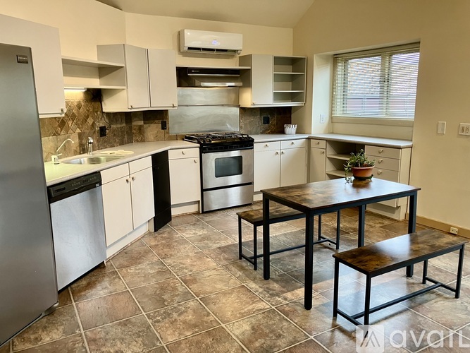 A kitchen with a table and chairs in front of a stove and oven.