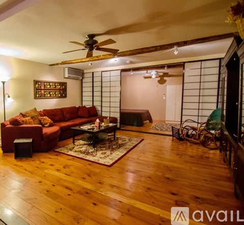 A living room with wooden floors and a red couch.